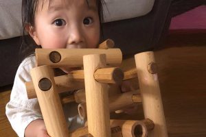 赤ちゃんが、無垢材でできた積み木の木のおもちゃで遊んでいる。