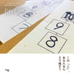 「子どもが手描きで書いた数字や文字を並べた紙の写真。『この“じ”、あなたならどう残す？』というメッセージが添えられている。」 おちびさんのもじとけい