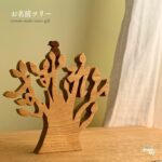 木製のお名前ツリーと上にとまる小さな鳥のパーツが置かれたナチュラルなギフト作品