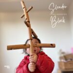 木の穴と形を活かした知育ブロック「スレンダーブロック」で遊ぶ子どもの様子。バランスを考えながら積み上げている。