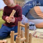 おうちで木の知育ブロックを組み立て、椅子を作って遊ぶ子どもの様子