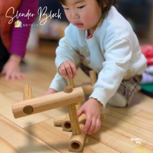 木製の知育ブロック「スレンダーブロック」で遊ぶ子ども。集中して組み立てる様子。
