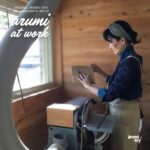 天然木の掛け時計「おちび時計」の本体を、木工アーティストが工房で木目を確認しながら手作業で制作している様子