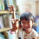 木製のひも通しおもちゃを楽しそうに持つ子ども。指先を使って遊ぶ知育おもちゃの様子。