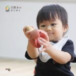 赤ちゃんが天然木のガラガラを握って遊んでいる様子｜出産祝いに人気の木のおもちゃ